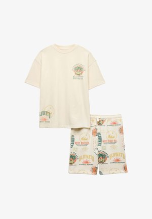 Beżowy t-shirt z krótkim rękawem i pasujące szorty z kolorowym tropikalnym tekstem i grafikami plażowymi.