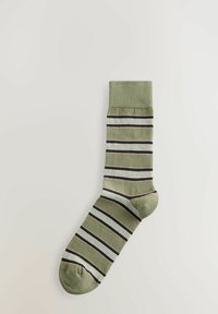 Chaussette en coton vert avec des rayures horizontales en bleu marine, crème et rouille. Elle présente une bordure côtelée et une forme de chaussette standard avec un renforcement à la pointe.