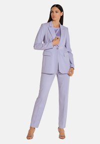 Lichtpaars op maat gemaakt pak met een blazer met één knoop, twee frontzakken en rechte broekspijpen. Satijnen top eronder versterkt de uitstraling.