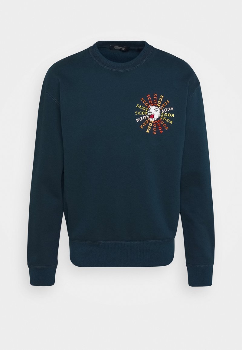Felpa girocollo di un blu scuro con un colorato ricamo di una testa di orso ruggente e il testo "Scotch & Soda" che la circonda sul lato sinistro del petto.