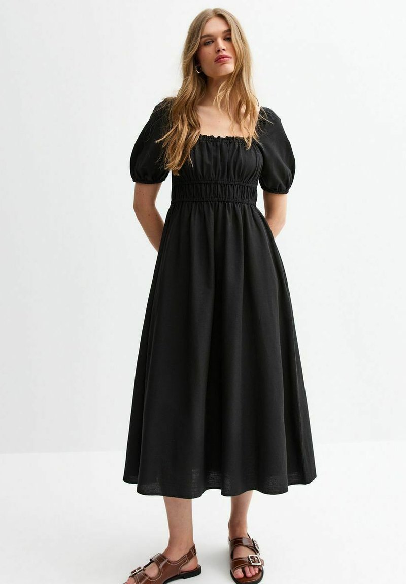 Vestido negro midi con un corpiño ajustado con fruncidos, mangas abullonadas y una falda fluida. Fabricado con un tejido ligero, que ofrece una textura suave.
