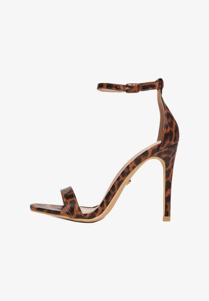 Sandalia de tacón de aguja alto con estampado de leopardo, correa al tobillo y diseño de punta abierta sobre fondo blanco.