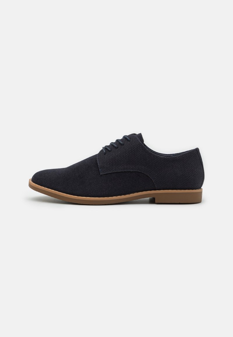 Chaussures bleu marine à lacets en tissu texturé avec un bout lisse et une semelle en caoutchouc, présentant un détail de surpiqûre contrastante subtile.