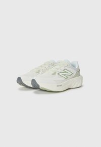 White athletic shoes with a textured mesh upper, pale green accents, a cushioned sole, and a gray rubber outsole. Features lacing system.