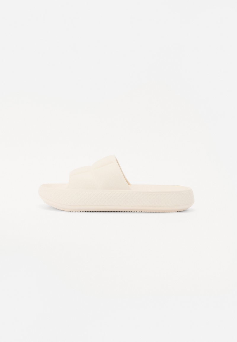 Ljusbeige slip-on sandal med en texturerad sula, som har en enkel tvåremdesign och slät yta.