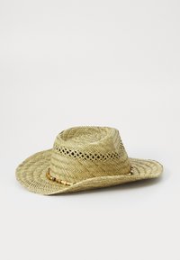 Sombrero de paja de ala ancha con un patrón tejido, que presenta un acento decorativo de cuentas alrededor de la corona. Color beige natural y acabado texturizado.