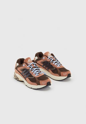 Paire de baskets Adidas marron et pêche avec semelles blanches et lacets bleu clair sur fond uni clair.