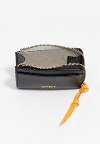 Czarny skórzany portfel z złotym zamkiem, częściowo otwarty, z beżowym materiałowym wnętrzem, złotym logo oraz żółtym skórzanym chwostem przy zamku na białym tle.