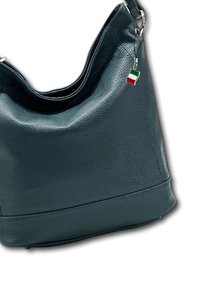 Sac hobo en cuir vert avec une finition texturée, présentant un sommet courbé et un petit pendentif en forme de drapeau italien attaché à la sangle.