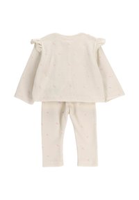 Kremowy strój dla niemowlęcia z długimi rękawami i spodniami, zdobiony małymi różowymi kwiatowymi wzorami oraz falbaniastymi detalami na ramionach bluzki.