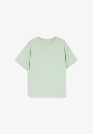 Jasnozielona bawełniana koszulka z krótkim rękawem, okrągłym dekoltem i małym kwiatowym wzorem w tym samym kolorze po lewej stronie klatki piersiowej.