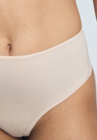 Beige, hoch taillierte Unterwäsche mit glattem, nahtlosem Material. Verfügt über einen weichen, elastischen Bund und minimale Nähte für optimalen Komfort.