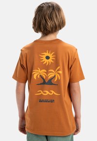 Oranje katoenen T-shirt met op de achterkant een zon, palmbomen en golven in zwarte en gele graphics. Korte mouwen en een losse pasvorm.
