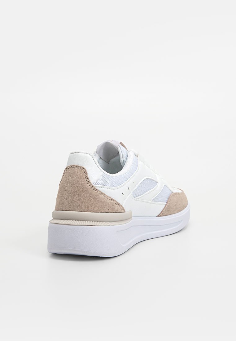 Baskets blanches avec des accents en mesh et en suède, présentant une semelle flexible, un bout arrondi et des détails beige clair sur le talon.