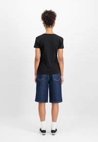 Čierne tričko s krátkymi rukávmi, denimové šortky, biele ponožky a čierne tenisky. Zadný pohľad na jednoduchom bielom pozadí.