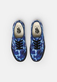 Niebieskie trampki z płótna z wzorem błyskawic, czarnymi sznurówkami i czarnymi gumowymi podeszwami. Zawierają logo Vans na wkładce.