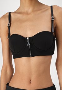 Svart bustier-top i slät tyg, med en framdragkedja, formade kupor och justerbara axelremmar i läder.