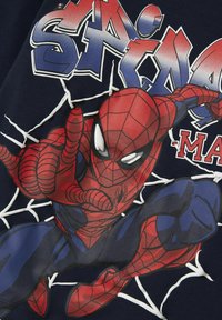 Granatowa koszulka z dużą, kolorową grafiką Spider-Mana, z czerwonymi i niebieskimi akcentami, białymi efektami sieci oraz wyrazistymi elementami tekstowymi.