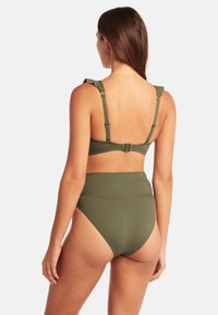 Olivgrünes Bikini-Set mit einem Oberteil mit verstellbaren Trägern und Rüschendetails, ergänzt durch hochgeschnittene Bikini-Höschen.