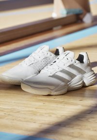 Baskets de sport blanches avec tige en maille texturée, trois rayures argentées et une semelle durable. Dispose d'un bout arrondi et d'un col rembourré pour le soutien.