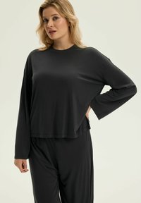 Czarny top z długim rękawem o luźnym kroju i okrągłym wykończeniu. Wykonany z gładkiego materiału, z opadającymi ramionami i okrągłym dekoltem.