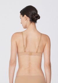 Nackter BH mit verstellbaren Trägern und Rückenschließe, nahtloses Design, weiche Textur und minimalistisches Aussehen, geeignet für Unterwäsche.