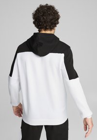 Hoodie s kombinacijom crnih i bijelih panela. Mekani materijal, duži rukavi i opušteni kroj. Ima veliki kapuljaču na leđima.