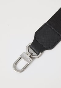 Zwarte nylon band met een gestructureerde oppervlakte, voorzien van een zilveren metalen clip aan één uiteinde, ontworpen voor duurzaamheid en een veilige bevestiging.