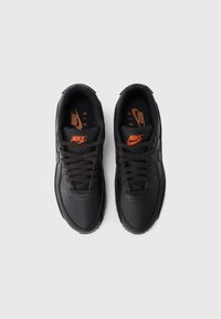 Adidașii Nike negri au un superior din piele, vârf rotund, șireturi negre și branding portocaliu pe laturi și pe branțuri. Talpă plată din cauciuc.