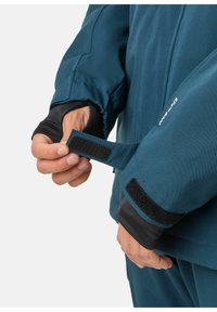 Teal Softshelljacke mit verstellbarem Klettverschluss an den Bündchen. Ausgestattet mit schwarzem Innenärmel für zusätzlichen Komfort und gesteppten Details. Verstecktes Verschlussdesign.