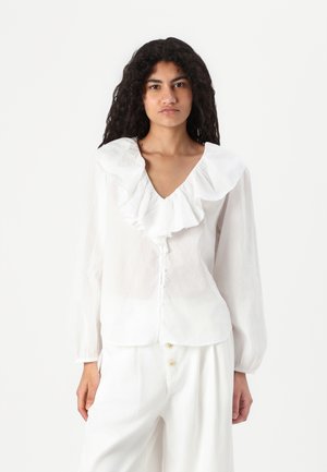 White long-sleeve blouse with a ruffled collar, v-neckline, and button front. Made from a light, textured fabric.