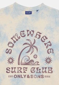 Svetlomodré tričko z bavlny s motívom tie-dye, ozdobené potlačou s textom: "Somewhere Surf Club" a grafikou palmy, vlny a slnka v tmavohnedej farbe.