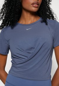 Navy blue athletic t-shirt with crew neck, short sleeves, and a twisted design at the front; features a small reflective Nike logo.