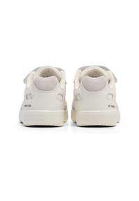 Hvide lædersneakers med en glat overflade, udstyret med en velcro-rem, rund tå og teksturerede accenter på hælen.