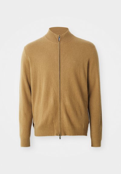 Kamelinės spalvos pilno užtrauktuko megztinis su aukšta apykakle, ilgomis rankovėmis, raukšlėtais manžetais ir subtiliu siuvinėtu logotipu ant krūtinės.