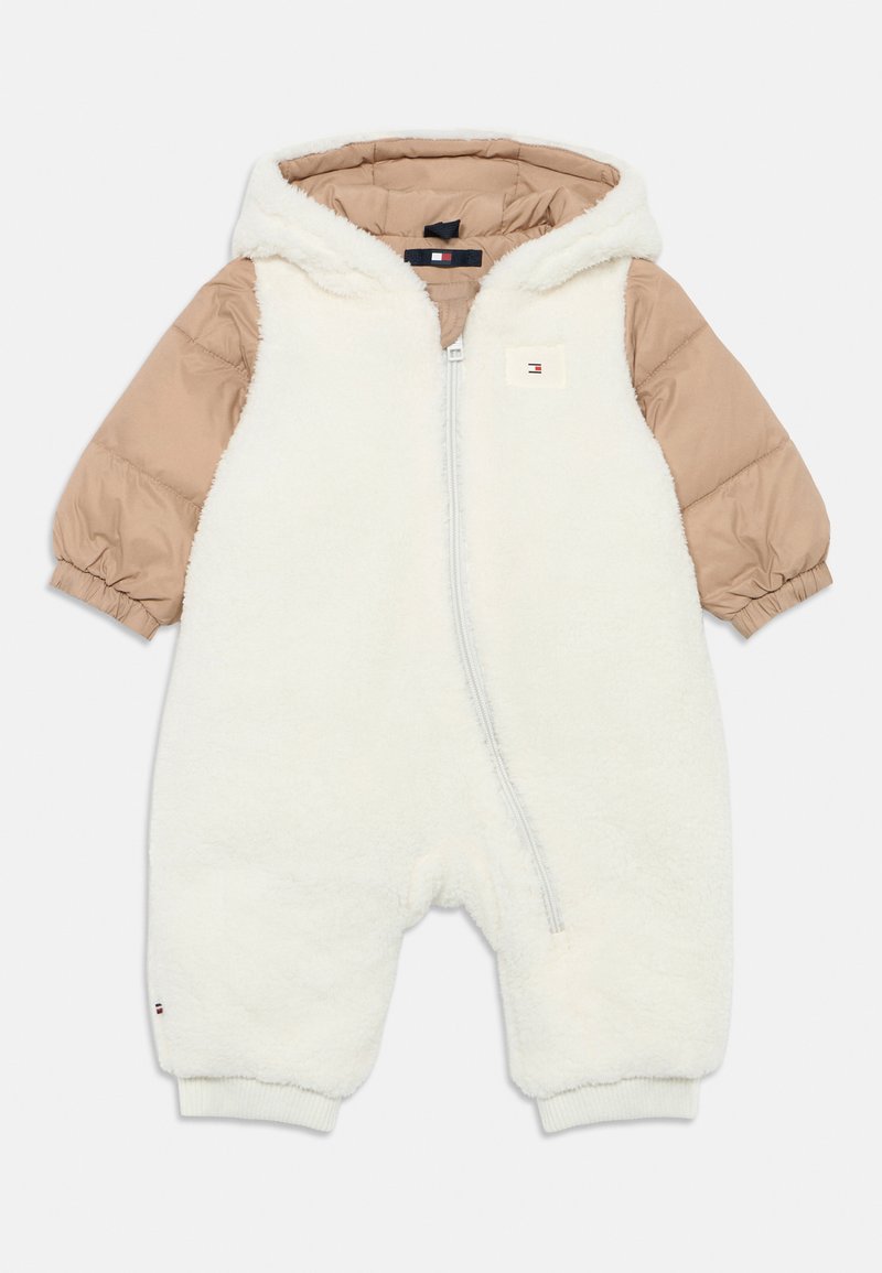 White fleece one-piece suit with beige quilted sleeves and hood, featuring a front zipper and logo patch on the chest.