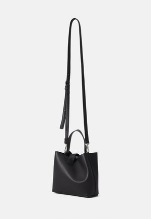 Sac à main en cuir noir avec poignée courte sur le dessus et longue bandoulière réglable sur fond blanc.