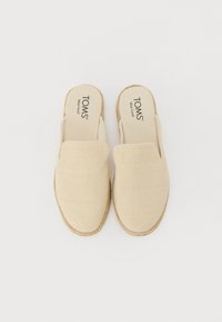 Bežiniai slip-on tipo batai su tekstūruotu audiniu, espadrilėms būdingu virvele aptrauktu padu ir plokščiu padu. Logotipas atspaudžiamas viduje.