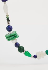 Perlenkette mit grünen, blauen und weißen Edelsteinen in verschiedenen Formen, darunter rund, scheibenförmig und tropfenförmig, mit silbernen Akzenten.