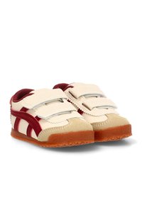 Las zapatillas cuentan con una parte superior de ante y malla en color beige, con acentos de cuero rojo, triple correa de gancho y bucle, y una suela de goma marrón.