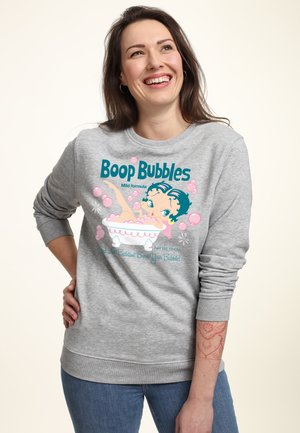 Grå sweatshirt med lange ærmer, der har et farverigt tegneseriedesign af en figur i et badekar omgivet af lyserøde bobler og tekst.