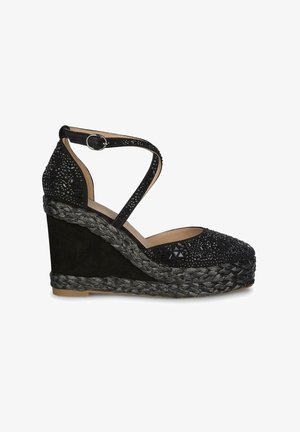 Sandale à talon noire avec un dessus en suède texturé, embellie de perles à motifs. Dotée de brides autour de la cheville et d'une plateforme en jute tressé.
