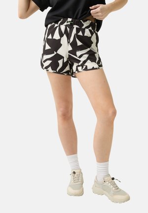 Zwart-witte gestreepte short met een elastische tailleband, met een geometrisch ontwerp. Draagt een crème kleurige sneaker en witte enkelsokken.