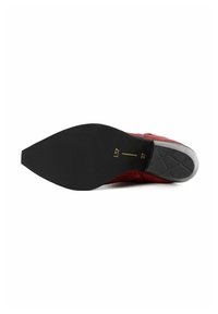 Zapato de ante rojo con suela de goma negra, con punta afilada y detalles texturizados en la parte superior. Incluye marcas de talla en la suela.