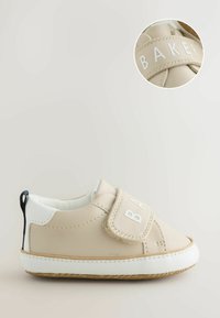 Chaussures pour bébé en similicuir beige avec une semelle en caoutchouc blanche, dotées d'une large sangle portant l'inscription "BAKER" et d'un accent de talon noir contrastant.
