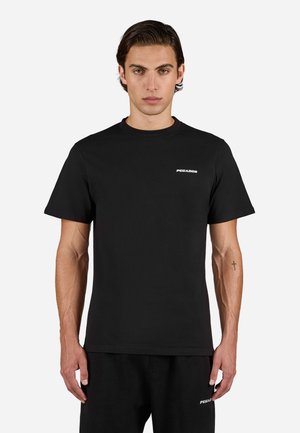 Sort bomulds T-shirt med korte ærmer og rund halsudskærning. Har et hvidt logo på venstre brystområde. Kombination med sorte bukser.