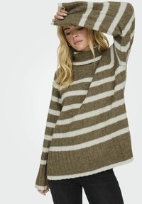 Raidallinen villapaita oliivinvihreänä ja kermaisenvalkoisena, korkea kaulus, ribattu pinta ja pitkät hihat. Ominaisuuksina rento ja väljä istuvuus.