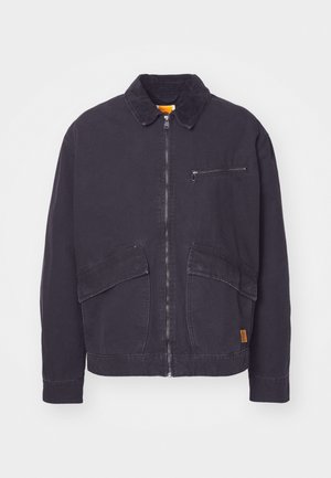Dark navy jacket with a corduroy collar, front zip closure, and two large patch pockets. Features a zippered chest pocket and subtle branding.