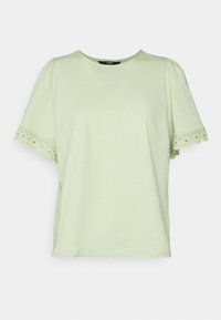 Camiseta de algodón verde claro con mangas cortas y abullonadas. El dobladillo presenta bordes decorativos con formas scalloped y pequeñas perforaciones en forma de ojal. Diseño de cuello redondo.