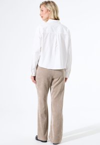 Witte lange mouwen shirt met een achterpand, gecombineerd met beige corduroy wide-leg broeken, met verticale ribbels en een gladde textuur.